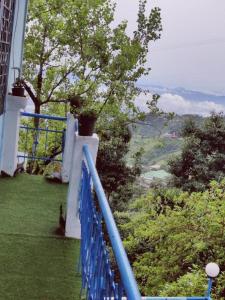 a blue railing on a balcony with a view of a tree at The HappyTel in Mussoorie