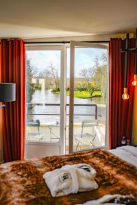 a hotel room with a bed with a view of a balcony at Hôtel-Restaurant Bel Ami in Pacy-sur-Eure