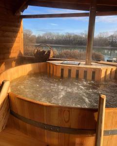 una vasca idromassaggio su una terrazza in legno con vista sul lago di Vízparti Apartmanház a Leányfalu