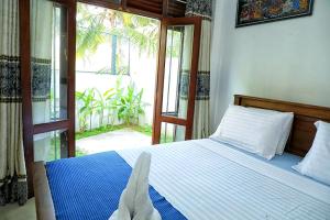 ein Schlafzimmer mit einem Bett und einem großen Fenster in der Unterkunft Ranil Villa in Galle