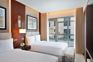una camera d'albergo con due letti e una finestra di The Townhouses The Pearl a Doha