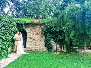 a bride and groom standing next to a stone wall at Vízparti Apartmanház in Leányfalu