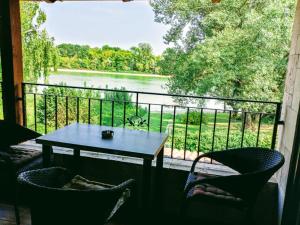 a table on a balcony with a view of a river at Vízparti Apartmanház in Leányfalu