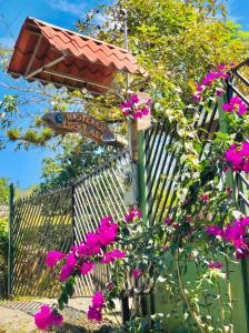 un cartello stradale con fiori rosa di fronte a una recinzione di Hospedaje Luis & Ana a Pejibaye