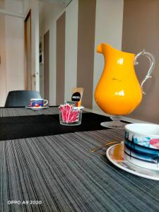 un vase jaune assis sur une table avec une plaque dans l'établissement Appartamento La Ninfea, à Arona