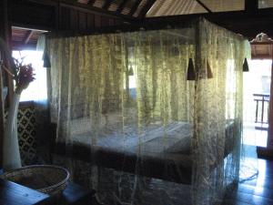 um quarto com uma cama com cortinas transparentes em Singko Lovina em Lovina