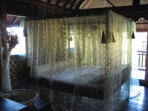 Cette chambre comprend un lit avec des rideaux transparents. dans l'établissement Singko Lovina, à Lovina