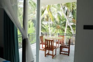 Zimmer mit einem Tisch und Stühlen auf einem Balkon in der Unterkunft Ranil Villa in Galle