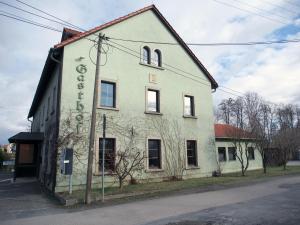 an old white building on the side of a street at Altes Teichhaus - Pension Ottendorf-Okrilla in Ottendorf-Okrilla