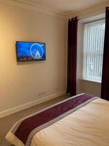 a bedroom with a bed with a tv on the wall at Apartment 39c in Oban