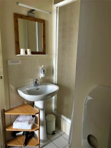 een badkamer met een wastafel, een toilet en een spiegel bij Le Vauban in Merville-Franceville-Plage