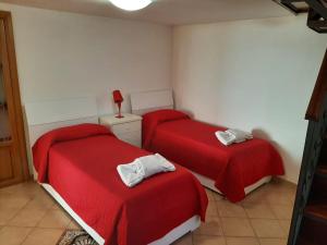 two beds in a room with red sheets at Villa Bebe' in Vico Equense