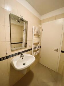 a bathroom with a sink and a mirror at Byblos Wellness Apartman Siófok By BLTN in Siófok