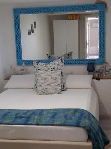 a bed with a blue headboard and a mirror at Casa Vacanza Paradise 1 in Marina di Campo