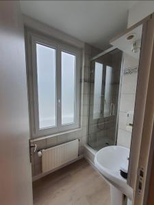 ein Bad mit einem weißen Waschbecken und einem Fenster in der Unterkunft New Windsor in Étretat