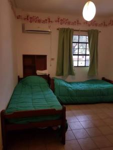 sypialnia z 2 zielonymi łóżkami i oknem w obiekcie Tu Lugar en Tucumán w mieście San Miguel de Tucumán