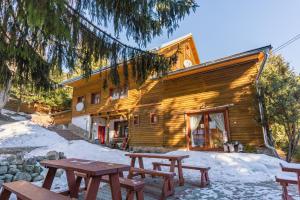 a wooden cabin with picnic tables in the snow at Penzión Javorina in Donovaly