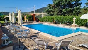 una piscina con sillas y sombrillas, una mesa y una estatua en B&B Ferro di Cavallo, en Tívoli