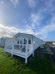 a white mobile home on the side of the road at E3 is a 2 Bedroom 6 berth Lodge on Whitehouse Leisure Park in Towyn near Rhyl close to beach with decking and private parking space This is a pet free caravan in Rhyl