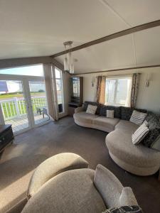 sala de estar con 2 sofás y balcón en E3 is a 2 Bedroom 6 berth Lodge on Whitehouse Leisure Park in Towyn near Rhyl close to beach with decking and private parking space This is a pet free caravan, en Rhyl