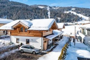 a snow covered house with a car parked in front at Souterrain Apartment Flachau in Flachau