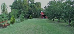 a large yard with a red house in the background at Cabaña Gota de Rocio en finca Margarita in San Rafael