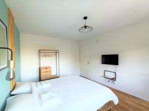 a white bedroom with a large bed and a tv at Studio lumineux bien placé en ville de Sion in Sion