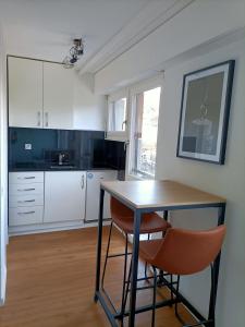 uma cozinha com armários brancos e uma mesa e cadeiras em Studio lumineux bien placé en ville de Sion em Sion