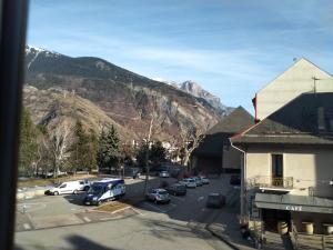 a town with cars parked in a parking lot with mountains at le petit SAINT ANTOINE in Saint-Jean-de-Maurienne