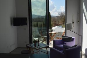 sala de estar con 2 sillas, mesa y ventana grande en Loft a Montepulciano sopra Birrificio artigianale, en Abbadia a Isola