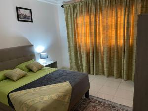 Un dormitorio con una cama con sábanas verdes y una ventana en Domaine des Maldives, en Yaoundé