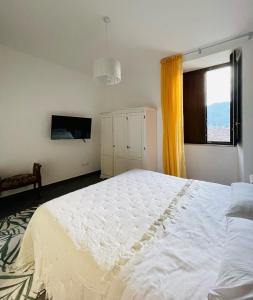 Un dormitorio con una gran cama blanca y una ventana en Palazzo Sabini, en Pertosa