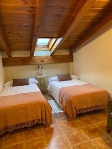 two beds in a room with wooden ceilings at Era de Parramon in Peramea