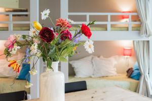 un vaso bianco con fiori su un tavolo in una camera da letto di Flo's Atelier - Family studio ad Amsterdam