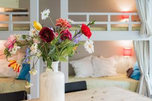 a white vase with flowers on a table in a bedroom at Flo's Atelier - Family studio NOTE studio is adjacent to Flo's apartment in Amsterdam