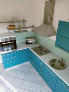 cocina azul con fregadero y fogones en La casa del cuore - Luxury Apartment, en Olgiate Comasco