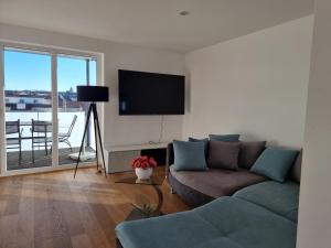ein Wohnzimmer mit einem Sofa und einem Flachbild-TV in der Unterkunft BodenSEE CITY APARTMENTS Friedrichshafen in Friedrichshafen