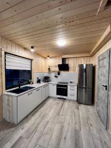a large kitchen with white cabinets and a wooden ceiling at Domki w Borach in Wycinki