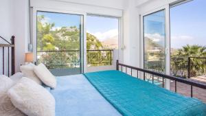 een slaapkamer met een bed en een balkon met grote ramen bij Villa Selene in Archangelos +15 foto's