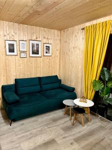 uma sala de estar com um sofá verde e uma mesa em Domki w Borach em Wycinki