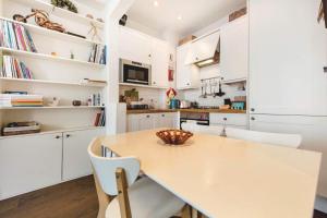cocina con armarios blancos, mesa y sillas en Franks Pied-à-terre in London-Quiet,Bright,Central, en Londres