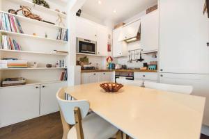 a kitchen with white cabinets and a table and chairs at Franks Pied-à-terre in London-Quiet,Bright,Central in London