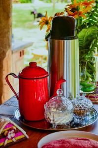a red coffee pot and a tea kettle on a table at Pousada Paraíso do Caju in Barreirinhas