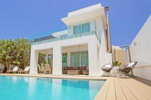 a villa with a swimming pool and two chairs at Villa Indigo in Protaras