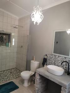 a bathroom with a toilet and a sink and a chandelier at Hartland Gastehuis/Guesthouse in Vredendal