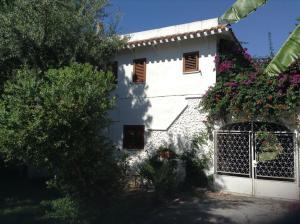 Biały dom z bramą i kwiatami w obiekcie Deliziosa Villa 150 metri dal mare w mieście Quartu SantʼElena