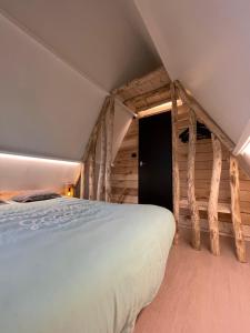 a large bed in a room with wooden walls at Sunclass Durbuy huisje 205 in Durbuy