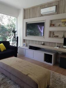 Una sala de estar con un televisor de pantalla plana en una pared. en Buzios Requinte & Sofisticação, en Búzios