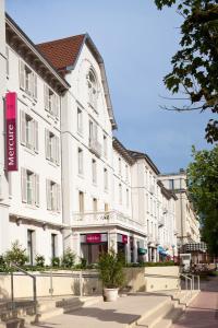 een groot wit gebouw aan de straatkant bij Hôtel Mercure Vittel in Vittel