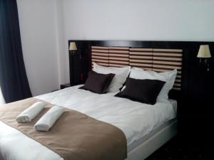 una camera da letto con un grande letto bianco con cuscini neri di Pensiunea Clasic a Curtea de Argeş